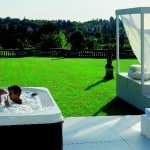Un jardin decorado con Jacuzzi, mesas y sillas chics